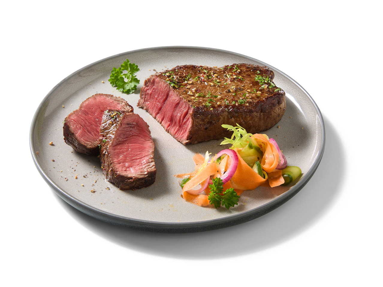 Steak de bœuf grillé avec salade de légumes frais sur une assiette grise.