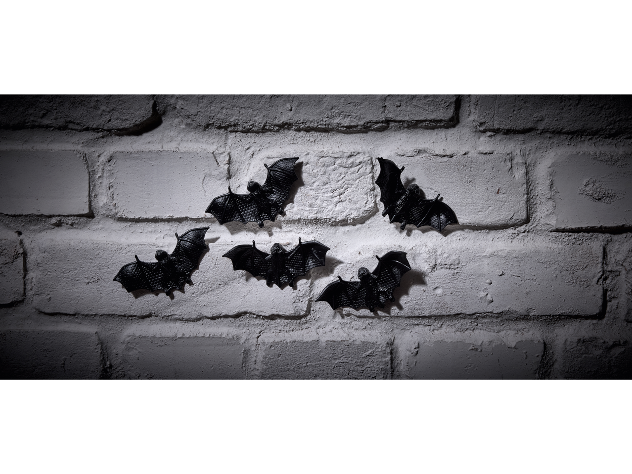 Black bat Halloween decorations on a white brick wall.