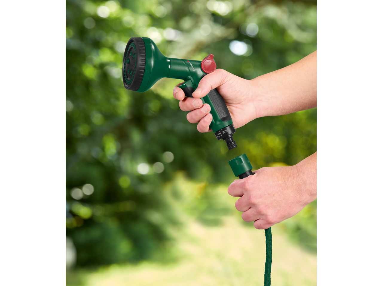 Mâini conectând un furtun de grădină flexibil PARKSIDE la un pistol de stropit.