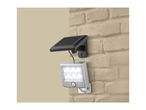 Wall-mounted solar LED spotlight with motion sensor on a brick wall