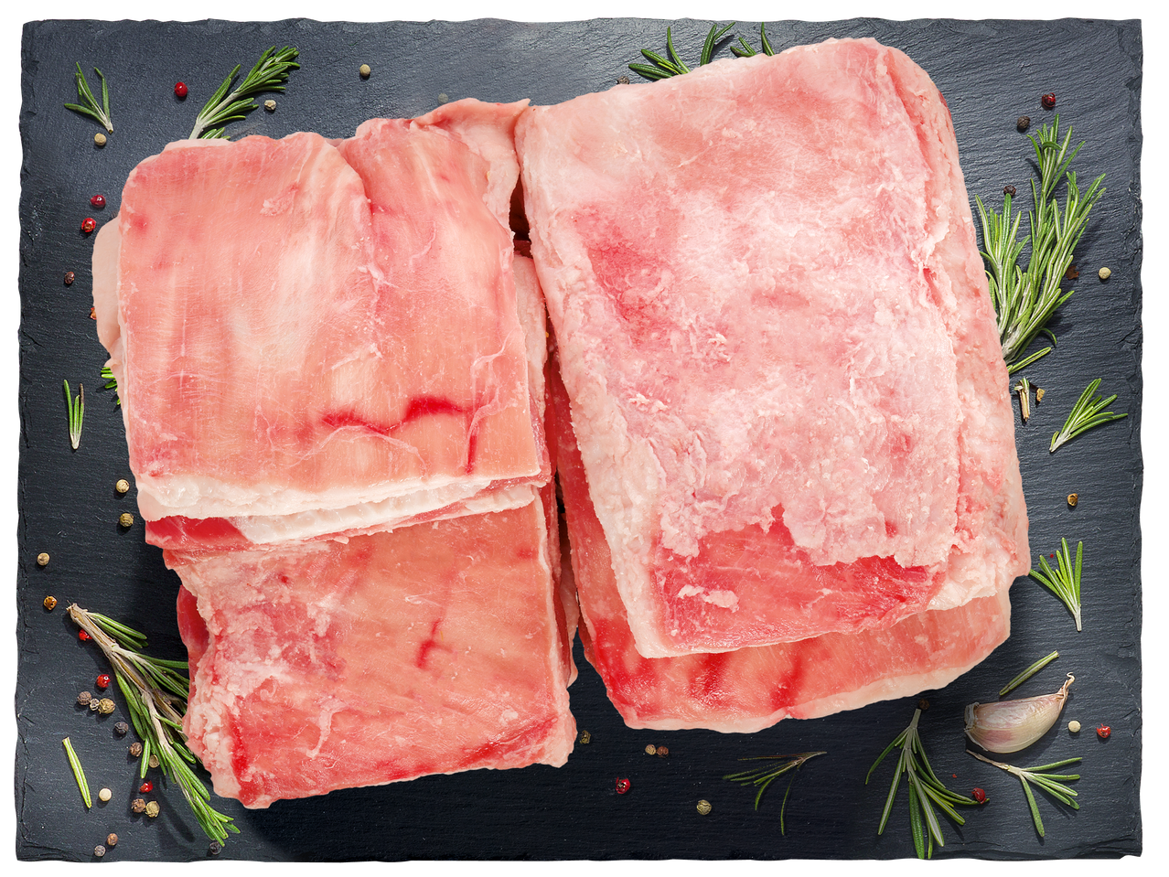 Сурови свински ребра с розмарин, чесън и черен пипер на черна дъска.