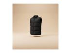 A black puffer vest floating against a beige background.