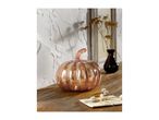 Rose gold glass pumpkin on a wooden surface with a dark vase and dried flowers.