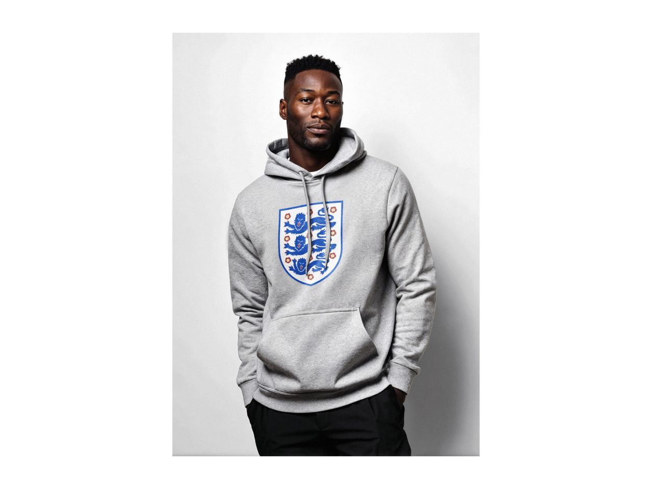 Man in a grey hoodie with an England football crest, hands in pockets.