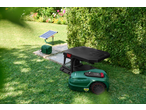 Robotic lawnmower with charging station and solar panel in a garden.