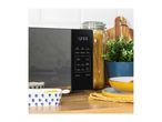 Black microwave oven with digital display showing 12:00, surrounded by kitchen items.