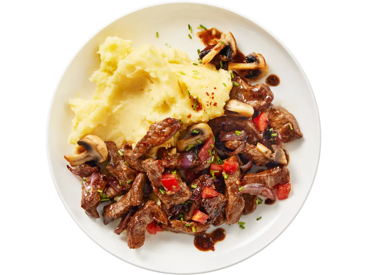 Diced beef steak with mashed potatoes, mushrooms, and vegetables on a white plate.
