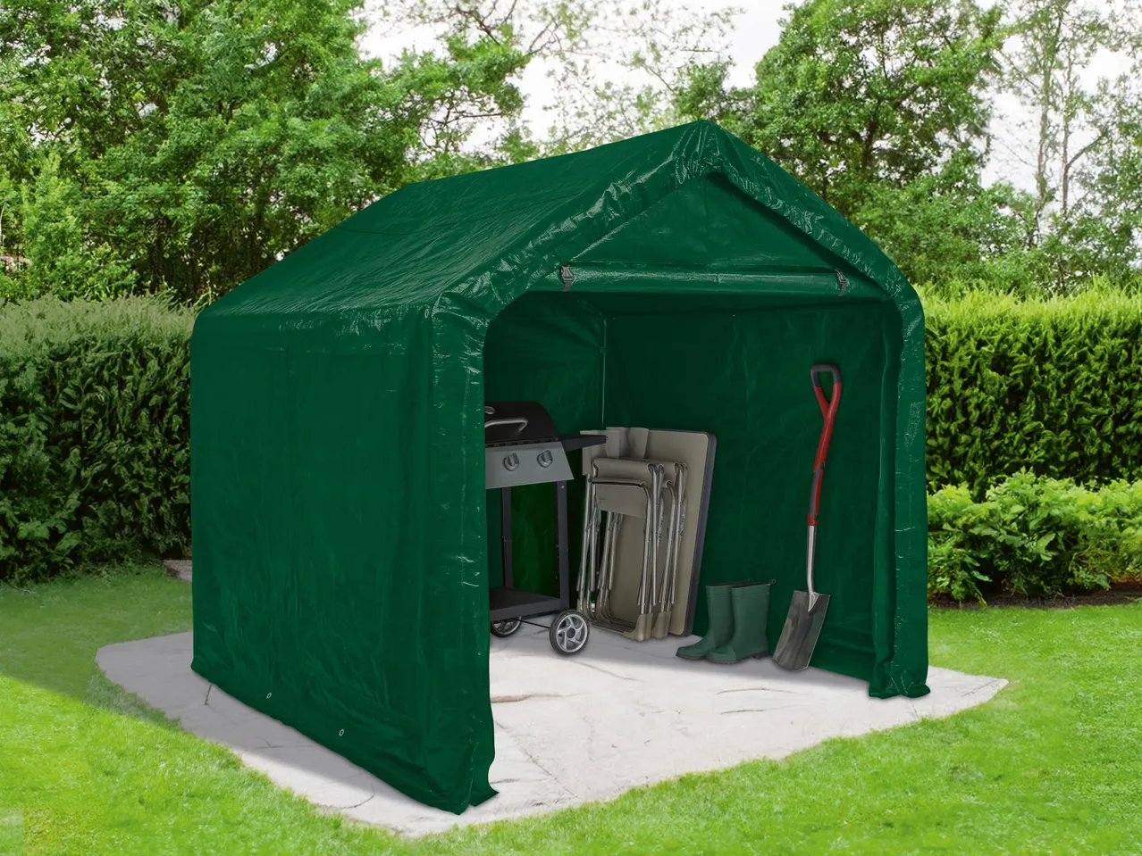 Tenda garage da esterno verde con barbecue, sedie pieghevoli, stivali e pala su un patio in cemento.