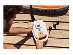 A person operating an electric pump to inflate an orange and white inflatable paddleboard on a wooden deck.