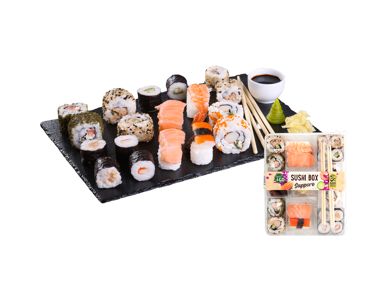 Veliki izbor sušija na crnoj ploči, uključujući nigiri, maki i uramaki, sa pakovanjem sušija sa strane.