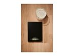 A black kitchen scale displaying '0 g' next to a glass bowl of flour on a wooden surface.