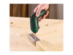 A person using a cordless screwdriver to attach a metal hinge to a wooden board.