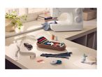A sewing machine and various sewing accessories arranged on a white table.