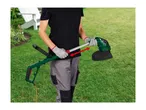 Person in work gloves holding a green and black electric grass trimmer with an orange cord.