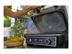 A person opening a grill with food cooking inside, with corn on the cob nearby.