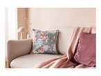 A light-colored sofa with a floral pillow, a pink throw blanket, and a ribbed pink pillow.