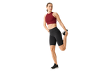 Femeie făcând stretching la picior, îmbrăcată cu un sutien sport și pantaloni scurți.