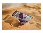 Red cabbage being shredded with a grater into a glass bowl on a wooden surface.