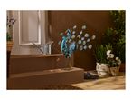 Decorative metal peacock with solar lights, watering can, and potted plants on a porch.