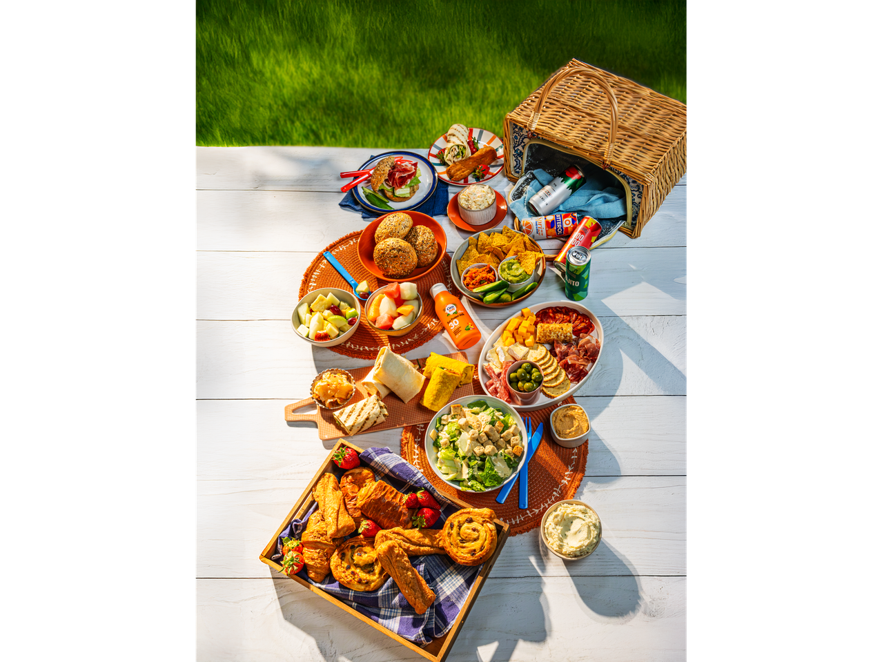 Summer picnic with salad, sandwiches, fruit, and drinks.