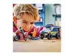 A boy playing with toy police car, motorcycle, and minifigures on a wooden surface.