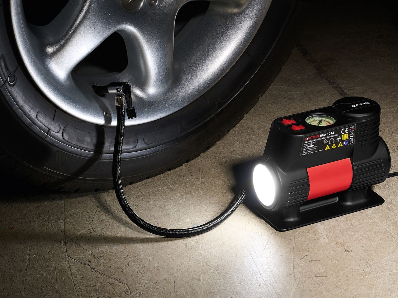 Ένας φορητός συμπιεστής αέρα με φως, συνδεδεμένος σε ελαστικό αυτοκινήτου.