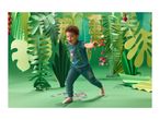 A boy in a green Paw Patrol t-shirt and joggers, playing with a puzzle in a jungle setting.