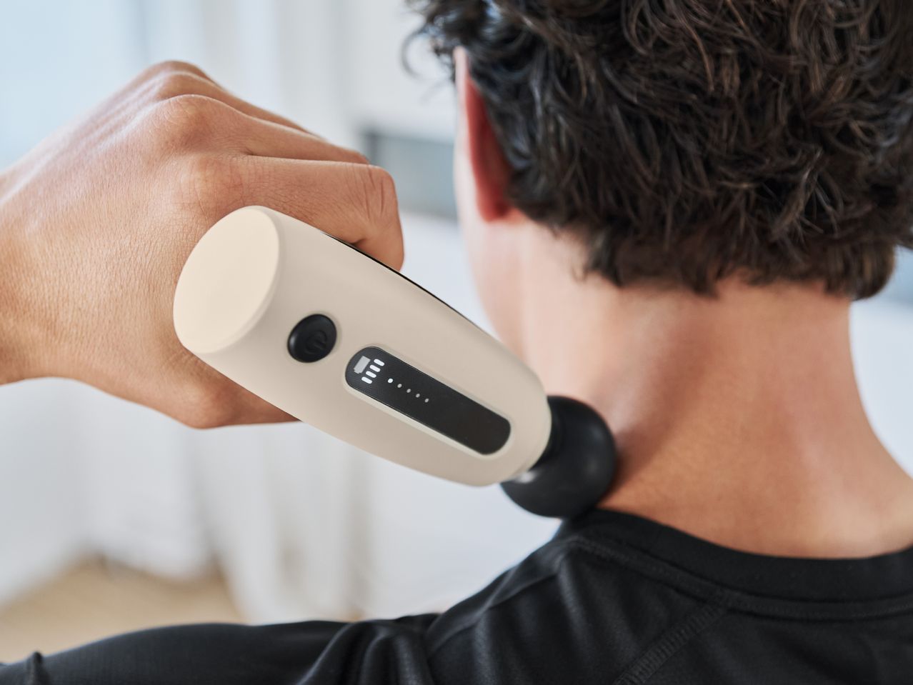 A person using a massage gun on their neck.