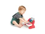Happy baby playing with a red and white toy piano with colorful keys and a screen.