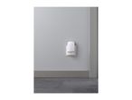 A white night light plugged into a wall outlet in a room with gray walls and floor.