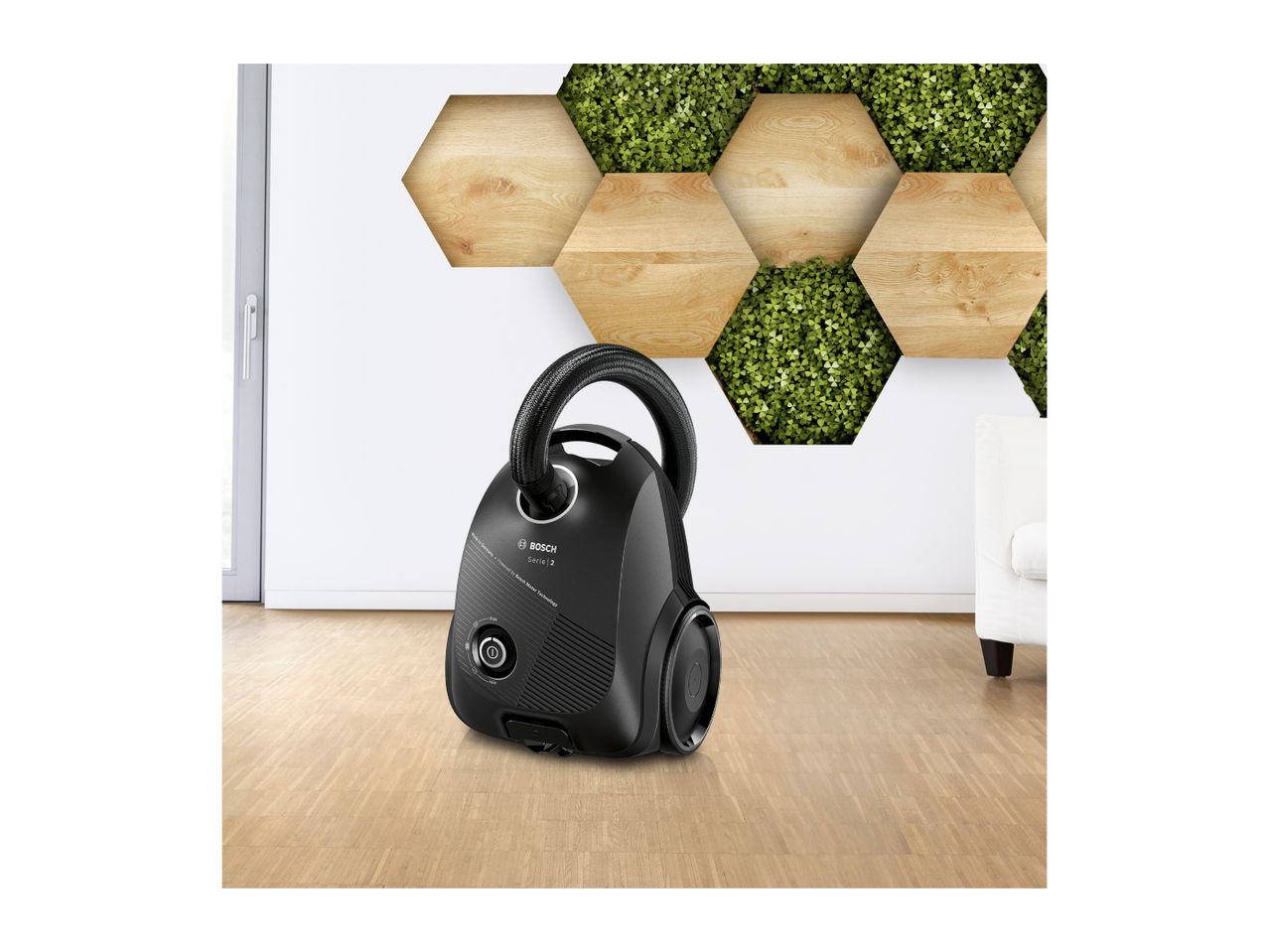 Black vacuum cleaner on a wooden floor with a hexagonal wall decoration