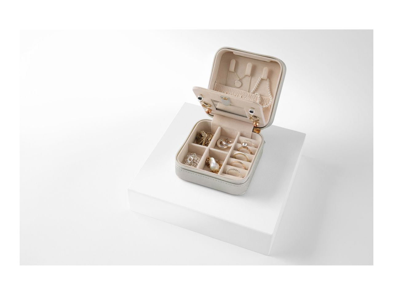 Beige jewelry box with compartments open, showcasing its interior organization.