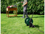 Cărucior pentru furtun PARKSIDE cu un bărbat udând flori într-o jardinieră de lemn.