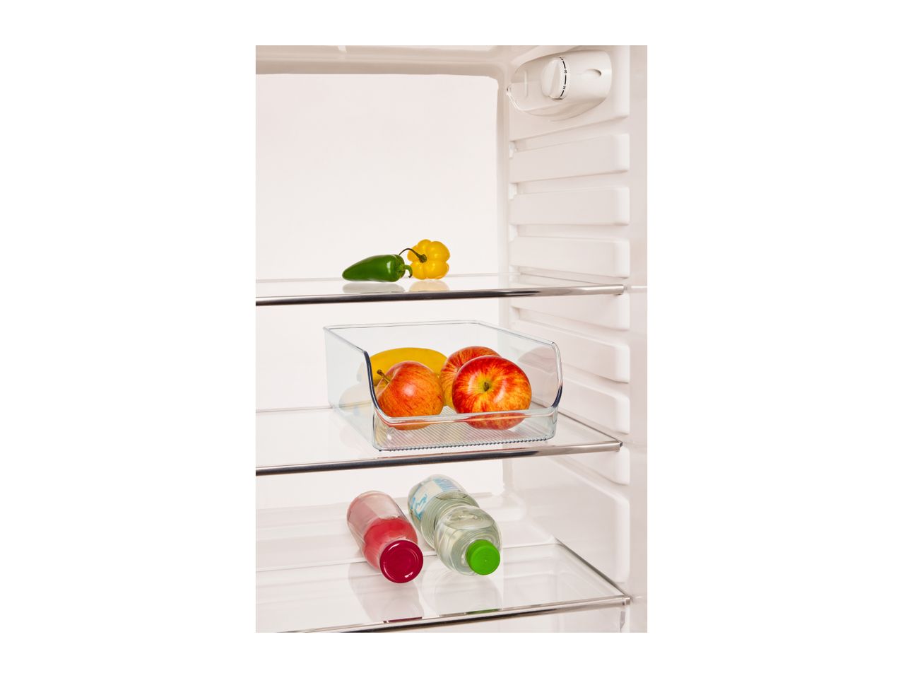 Open refrigerator with apples, bananas, peppers, and bottled drinks on shelves.