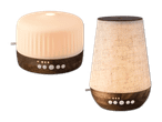 Zwei beleuchtete Aroma-Diffuser in verschiedenen Formen mit Holzsockel.