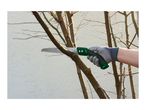 Hand in a grey glove holding a green pruning saw, cutting a tree branch.