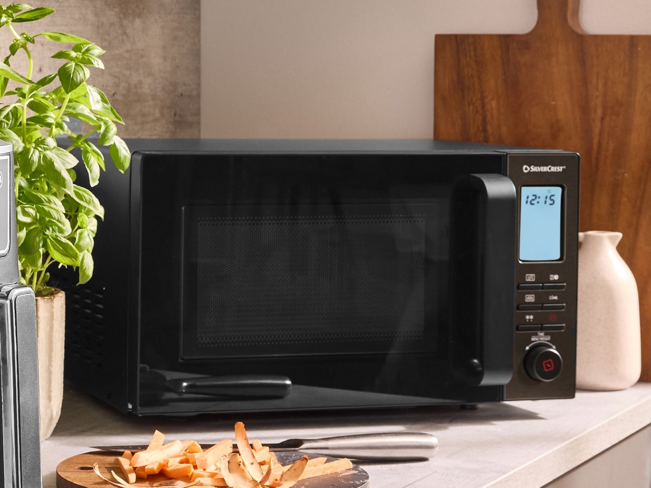 SilverCrest microwave oven on a kitchen counter with fresh basil and chopped vegetables