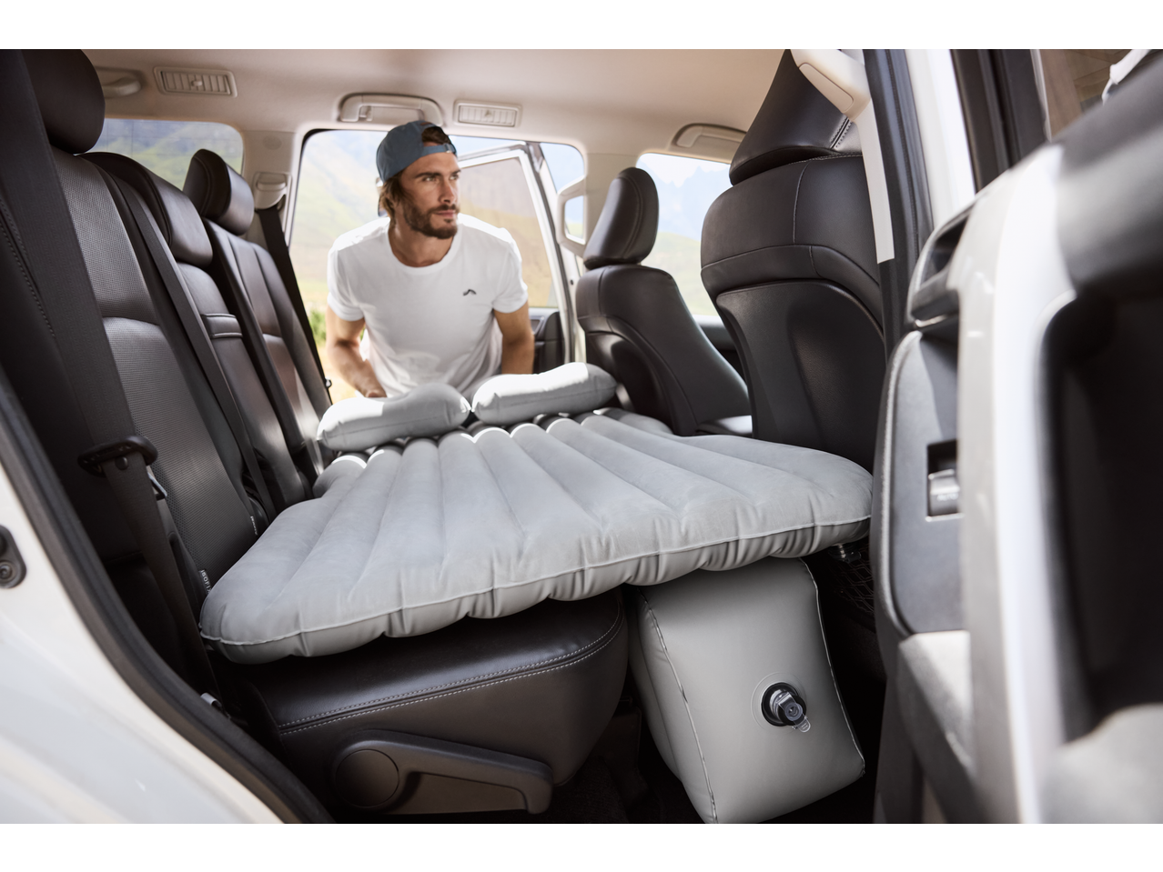 Bărbat instalează o saltea gonflabilă CRIVIT pe bancheta din spate a unei mașini.