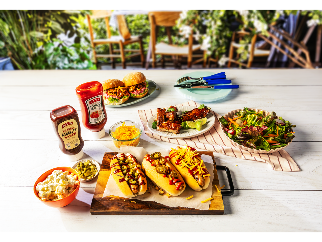 A summer BBQ feast featuring Batt's ketchup and BBQ sauce, hot dogs, pulled pork sliders, ribs, and salad.