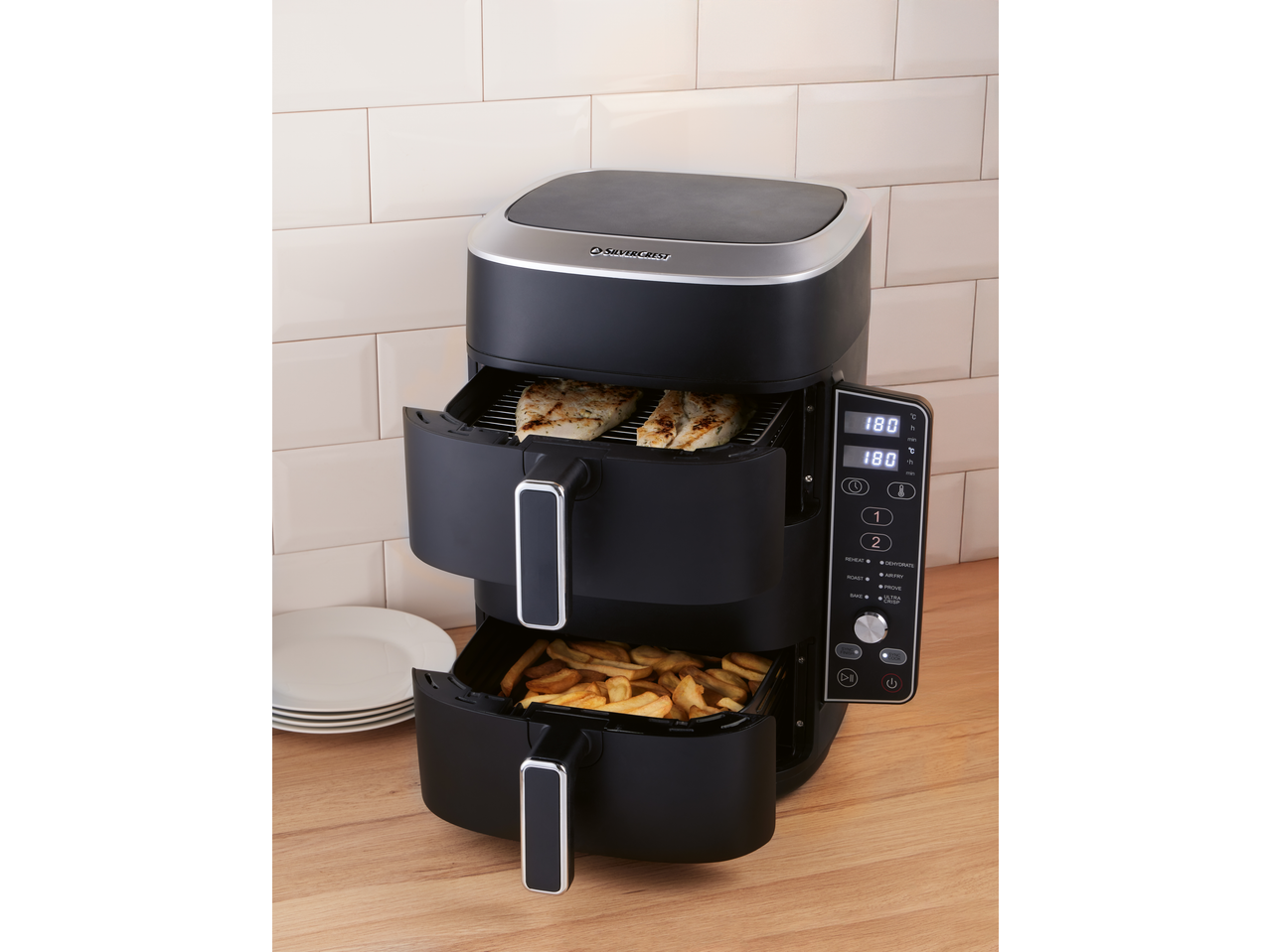 Dual-basket air fryer with chicken and fries, displaying 180°C on its digital screen.