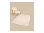 Cream armchair with wooden frame and a matching cream rug on a beige background.