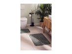 Bathroom with two striped bath mats, toilet, plant, and wooden vanity with sink.