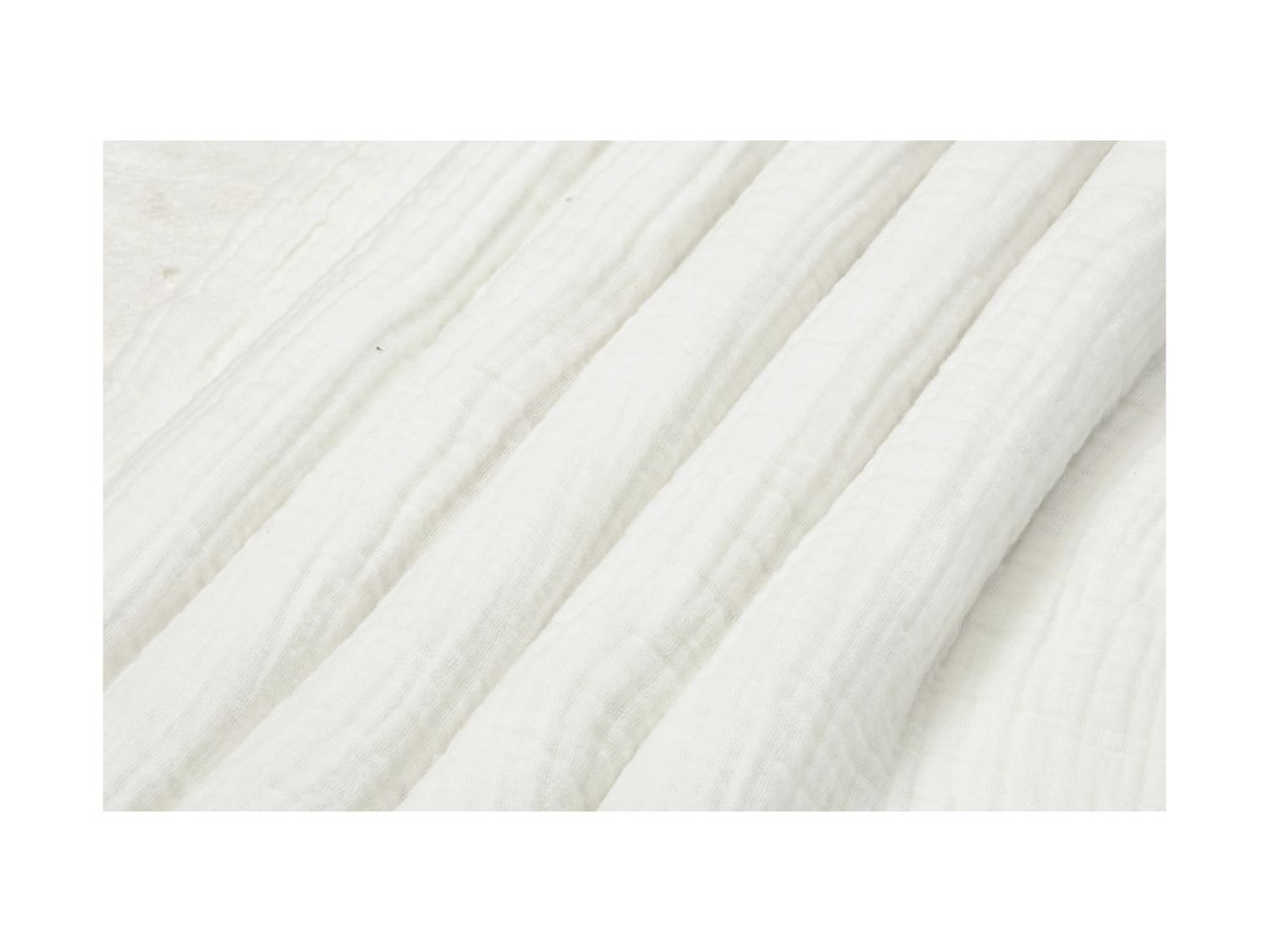 Close-up of white, textured muslin fabric with soft folds.