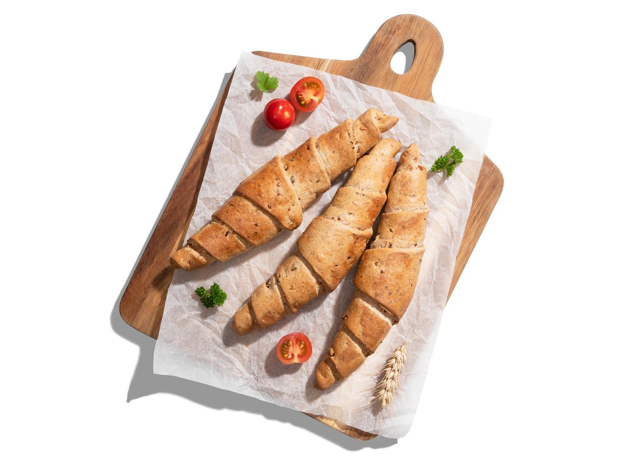 Három teljes kiőrlésű croissant fa vágódeszkán.