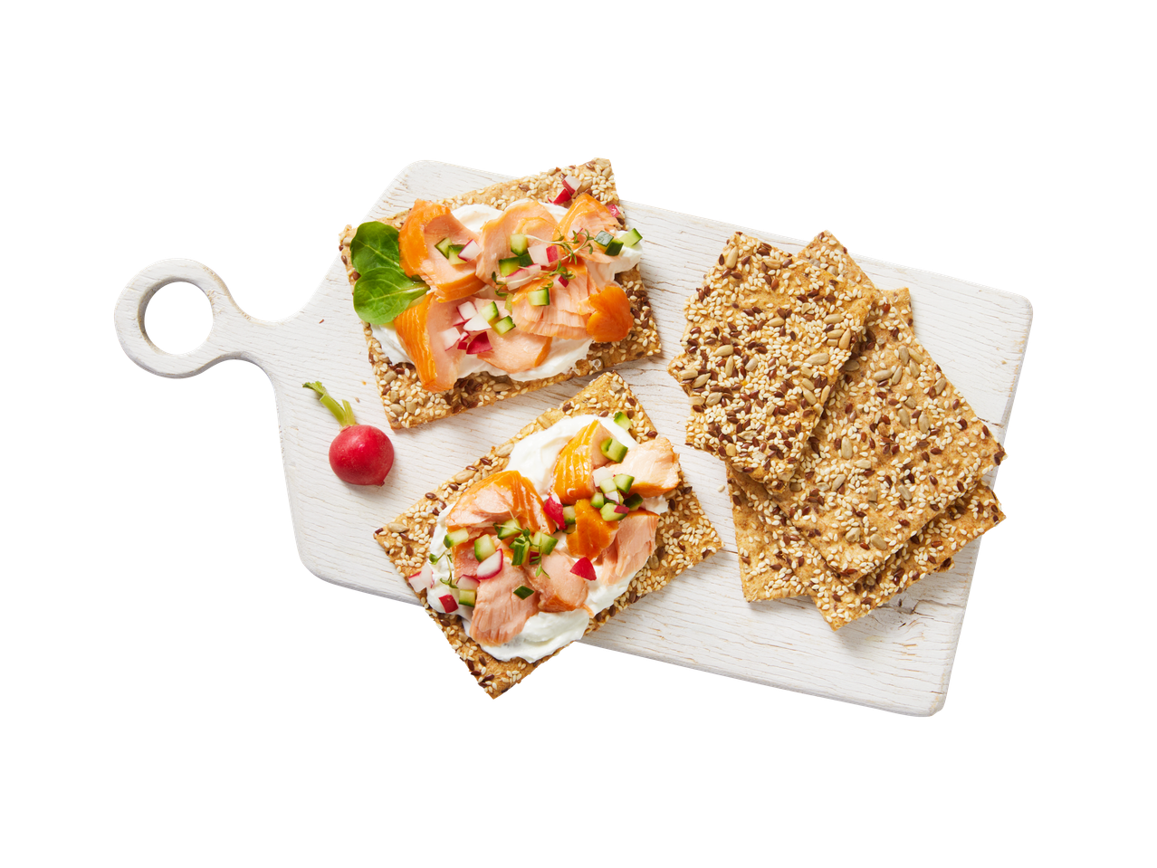 Crackers met gerookte zalm, roomkaas en groenten op een witte snijplank.