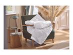 White quilted duvet draped over a green armchair, with a side table and lamp nearby.