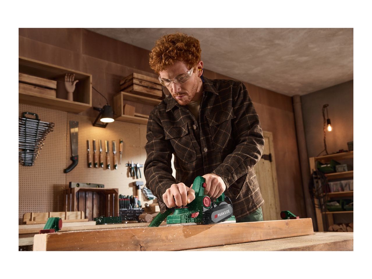 Man planing wood with an electric planer in a workshop.