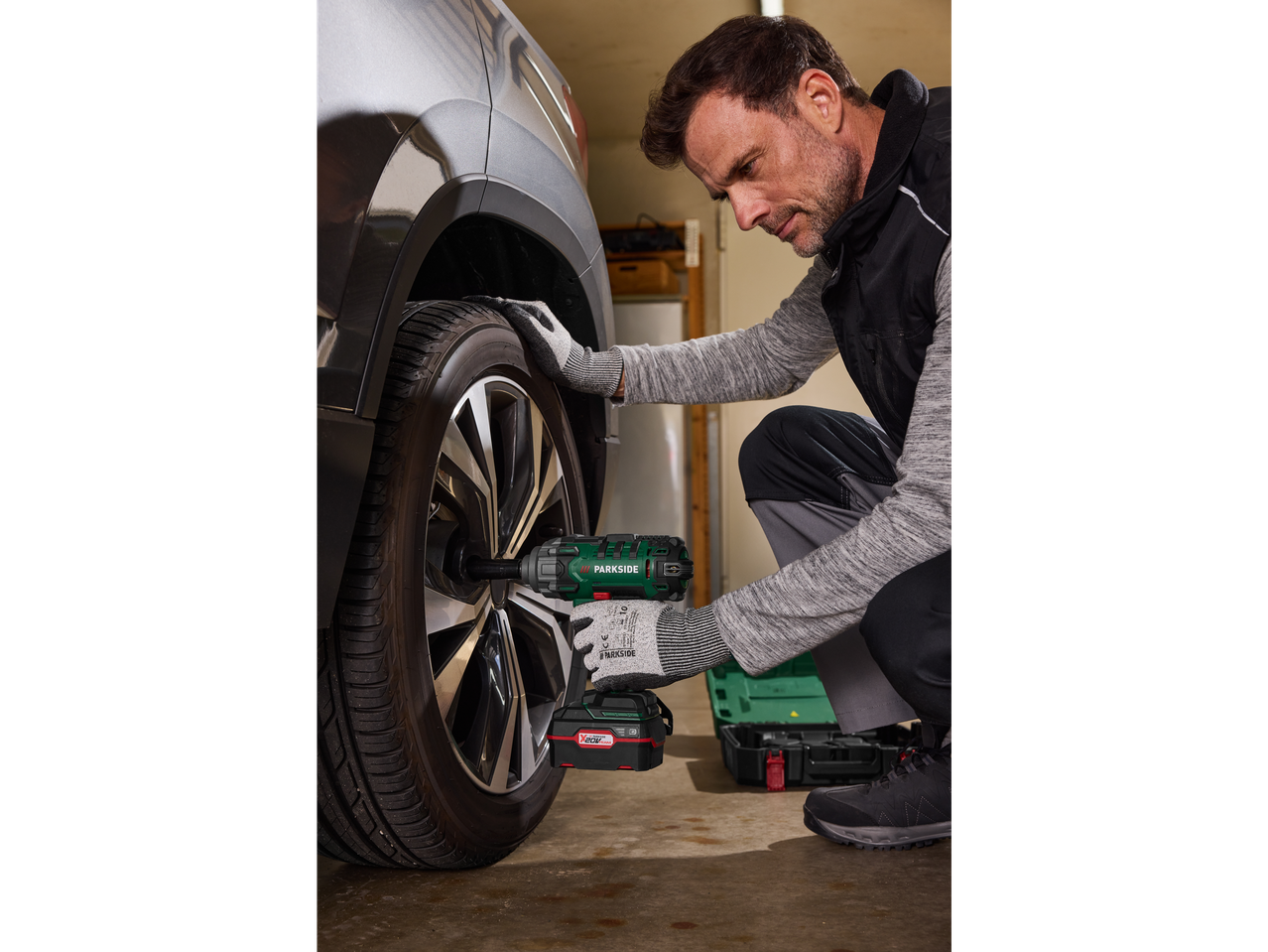 Vyras naudoja Parkside® smūginį suktuvą, dirbdamas prie automobilio rato.