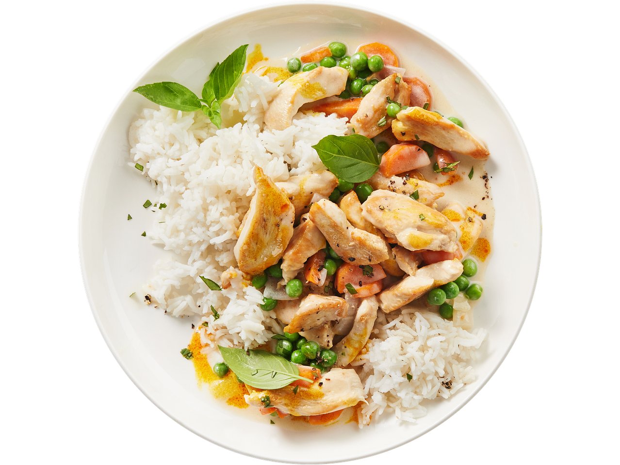 Chicken curry with rice, peas, and carrots, garnished with basil leaves on a white plate.