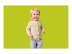Happy toddler in a beige cardigan and blue jeans on a green background.